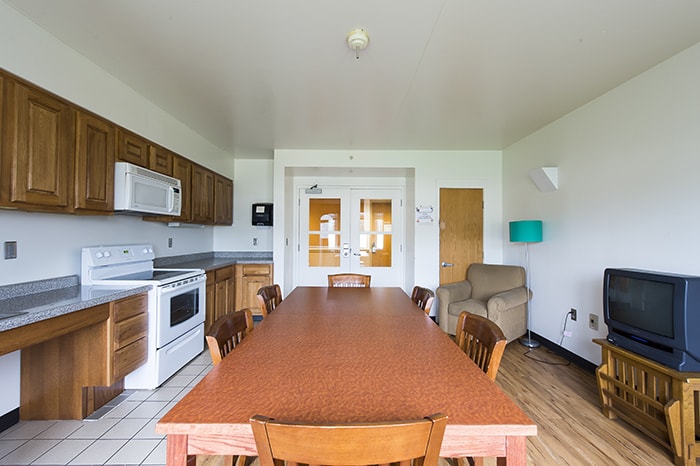 West Wing Community Kitchen - large dining table with chairs a tv and kitchen